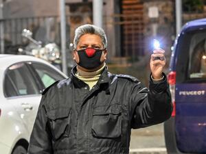 A man wearing a face mask holds a light during a flash mob " Italia Patria Nostra" (Italy Our Country) at the Garbatella district in Rome on March 15, 2020. Italy reacts with the solidarity of flash mobs circulating on social media to make people "gather" on balconies at certain hours, to show lights, candles, flashlights or smartphones's light. AFP/File