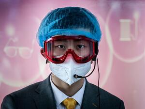 A worker at an information desk wearing protective gear as a preventive measure against the COVID-19 coronavirus looks on at a nearly empty arrivals area at Beijing Capital Airport in Beijing on March 16, 2020. China tightened quarantine measures for international arrivals as the country worries about a rise in imported cases of the deadly coronavirus and anger rages online at how Europe and the United States are handling the pandemic. NICOLAS ASFOURI / AFP