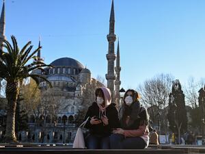 Women wear protective face masks sitting near the Sultanahmet Mosque also known as the Blue Mosque as the nation tries to contain the novel coronavirus, COVID-19, in Istanbul on March 17,2020. OZAN KOSE / AFP