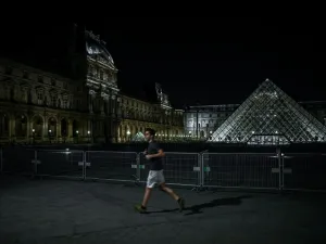 A man jogs past the Louvre Pyramid at night in Paris on March 18, 2020, as a strict lockdown came into in effect in France to stop the spread of COVID-19, caused by the novel coronavirus. A strict lockdown requiring most people in France to remain at home came into effect at midday on March 17, 2020, prohibiting all but essential outings in a bid to curb the coronavirus spread. The government has said tens of thousands of police will be patrolling streets and issuing fines of 135 euros ($150) for people wit