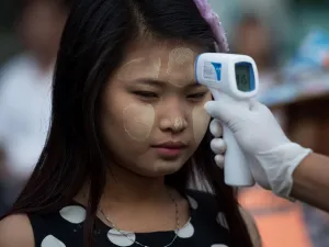 A woman wearing thanaka, a traditional facial cosmetic, has her temperature taken as a preventive measure against the COVID-19 novel coronavirus at a market in Yangon on March 21, 2020. Ye Aung Thu / afp