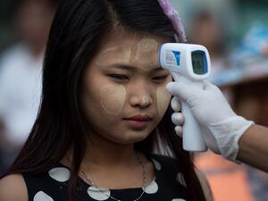 A woman wearing thanaka, a traditional facial cosmetic, has her temperature taken as a preventive measure against the COVID-19 novel coronavirus at a market in Yangon on March 21, 2020. Ye Aung Thu / afp