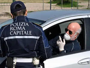 A member of the Rome Local Police checks the documents and the self-declaration of a motorist, wearing a facemask for protective reasons, on the Via Pontina, in Rome, on March 21, 2020, during the country's lockdown aimed at stopping the spread of the COVID-19. AFP/File