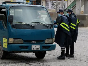Policemen speak to a truck driver at a checkpoint in the Jordanian capital Amman during a nationawide curfew imposed by the authorities in order to control the spread of the novel coronavirus, on March 21, 2020. Khalil MAZRAAWI / AFP