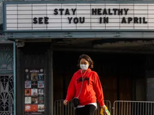 A woman walks wearing a mask to protect herself from the novel coronavirus (COVID-19) in front of a closed theater in Koreatown, Los Angeles, on March 21, 2020. All 40 million residents of California were on March 19 ordered to stay at home indefinitely in a bid to battle the coronavirus pandemic in the nation's most populous state. Apu GOMES / AFP