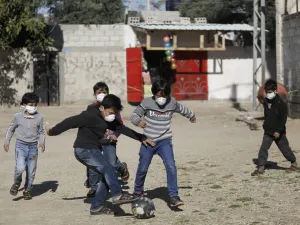 Boys wearing protective and N95 masks play with a football outside their homes in Gaza City on March 22, 2020. MOHAMMED ABED / AFP