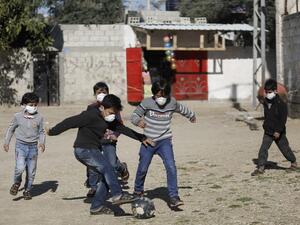Boys wearing protective and N95 masks play with a football outside their homes in Gaza City on March 22, 2020. MOHAMMED ABED / AFP