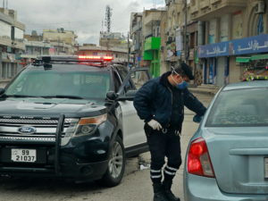 A policeman speaks to a driver at a checkpoint in the Jordanian capital Amman during a nationawide curfew imposed by the authorities in order to control the spread of the novel coronavirus, on March 21, 2020. Khalil MAZRAAWI/AFP