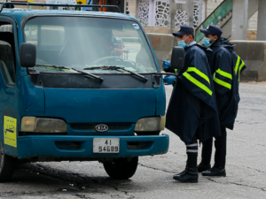 Policemen speak to a truck driver at a checkpoint in the Jordanian capital Amman during a nationawide curfew imposed by the authorities in order to control the spread of the novel coronavirus, on March 21, 2020. Khalil MAZRAAWI / AFP