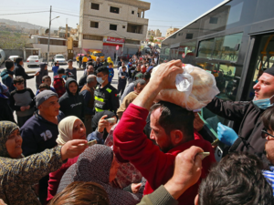 People queue to buy subsidised bread from a municipal bus in the Marka suburb in the east of Jordan's capital Amman on March 24, 2020, as the kingdom announced it would deliver bread and water supplies after the government decided to indefinitely extend a curfew amidst efforts to contain COVID-19 coronavirus disease. Khalil MAZRAAWI / AFP