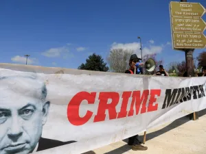 An anti-incumbent government protester waves an Israeli flag tainted in black in front of banner showing Israeli Prime Minister Benjamin Netanyahu, during a demonstration in front of the Knesset celebrating the resignation of the Knesset Speaker in Jerusalem on March 25, 2020. Yuli Eldenstein, th speaker of Israel's parliament, an ally of Prime Minister Benjamin Netanyahu, resigned, clearing the way for a vote that could see him replaced by an opponent of the embattled premier. Emmanuel DUNAND / AFP