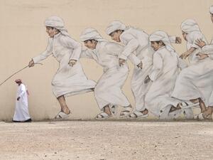 An Emirati man, wearing a protective face-mask, walks past a graffiti in Dubai on March 28, 2020. KARIM SAHIB / AFP