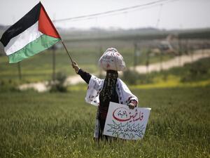 A Palestinian woman waves her national flag during an event marking Land Day near the Israel-Gaza border as mass rallies planned to commemorate the event were cancelled amid concerns about the spread of coronavirus disease (COVID-19), east of Gaza City, on March 30, 2020. MOHAMMED ABED / AFP