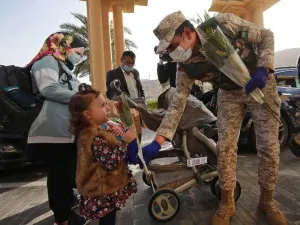 A Jordanian soldier greets people with flowers as they leave a Dead Sea resort where they have been quarantined for 14 days, approximately 60 kilometres sout of the Jordanian capital Amman on March 30, 2020. AFP