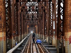 A maintenance worker, wearing a face mask as a preventive measure against the spread of the COVID-19 novel coronavirus, stands in the middle of the railway track on the Long Bien bridge in Hanoi on April 1, 2020. (AFP)