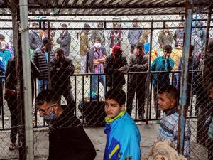 Migrants and refugees, some wearing facemasks for protective measures, queue in a makeshift camp next to the Moria camp on the Greek island of Lesbos on April 2, 2020. Over 20 coronavirus cases were found in a camp near Athens this week. At the camp of Moria on the island of Lesbos, both doctors and migrants say health precautions are not much help in a facility that is so badly overcrowded. The novel coronavirus could spread faster in overcrowded refugee and displaced persons camps than it has anywhere els
