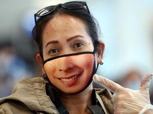 A woman displays her mask as Filipinos who availed general amnesty granted by the Kuwaiti government gather at the Kuwait International Airport Terminal 4, on April 3, 2020 on their home to Manila amid the coronavirus COVID-19 pandemic crisis. For systematic documentations, illegal expats from the Philippines, Egypt, India, Bangladesh, Sri Lanka and other countries were at first, requested to submit themselves at a school compound in Farwaniya arranged according to nationalities. YASSER AL-ZAYYAT / AFP
