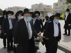 Pallbearers from the Ultra-Orthodox Jewish burial society (Hevrat kadishah), wearing surgical masks as a precaution against COVID-19 coronavirus disease, carry the coffin of an elderly man (not a COVID-19 victim) during a funeral outside the Shamgar funeral house in Jerusalem on April 5, 2020. MENAHEM KAHANA / AFP