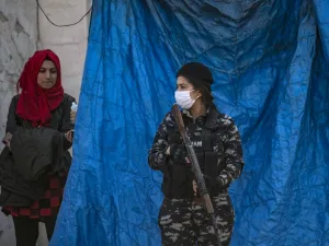 A member of Kurdish Internal Security wearing a protective mask stands guard as Kurdish Red Crescent medics check a passenger for COVID-19 symptoms upon arrival from the Syrian capital, at a mobile site just outside Syria's Qamishli airport in the northeastern Hasakeh province, on April 7, 2020. AFP/File