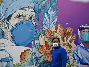 A man wearing a face mask walks in front of a mural at the Leishenshan Hospital that had offered beds for coronavirus patients in Wuhan, in China’s central Hubei province on April 11, 2020. Noel Celis / AFP