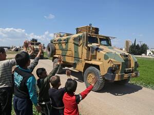 Syrian youths wave to a convoy of Turkish military reinforcements advancing near the town of Hazano in the countryside of Syria's Idlib province, on April 12, 2020, on the highway linking the Bab al-Hawa border crossing with Turkey to Idlib. Aref TAMMAWI / AFP