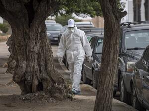 A Moroccan health worker wearing a protective outfit against the novel coronavirus walks in an empty street in the capital Rabat on April 12, 2020. FADEL SENNA / AFP