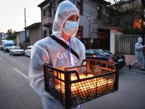 A church volunteer wearing protective equipment brings holy light to the people at their home during Christian Orthodox Easter celebration prior to the religious service held with closed doors due to the social distancing rules imposed by the state of emergency in Bucharest April 18, 2020, amid the COVID-19 pandemic caused by the novel coronavirus. Until now Romania registered 8,418 confirmed cases of people infected by coronavirus, 421 deaths and 1,730 healed persons. Daniel MIHAILESCU / AFP