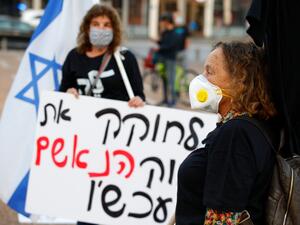 Israeli women wearing a face masks take part in a "Black Flag" demonstration, to protest against Prime Minister Benjamin Netanyahu and anti-democratic measures to contain the novel coronavirus outbreak, at Rabin Square in the coastal city of Tel Aviv, on April 19, 2020. JACK GUEZ / AFP