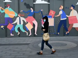 A woman wearing a face mask walks past a mall in Beijing on April 21, 2020. WANG ZHAO / AFP