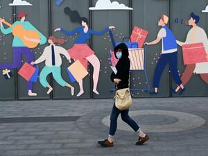 A woman wearing a face mask walks past a mall in Beijing on April 21, 2020. WANG ZHAO / AFP