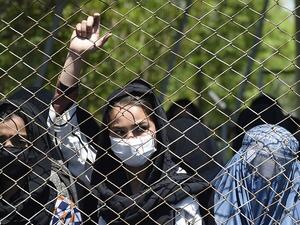 A women wearing a facemask peeks from a iron fence as they wait to receive free wheat from the government emergency committee during a government-imposed lockdown on the capital city as a preventive measure against the COVID-19 coronavirus, in Kabul on April 21, 2020. WAKIL KOHSAR / AFP