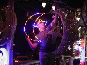 A Palestinian youth hangs decorative lights at a shop in east Jerusalem on April 21, 2020, as Muslims prepare for the start of the holy fasting month of Ramadan. Ahmad GHARABLI / AFP`