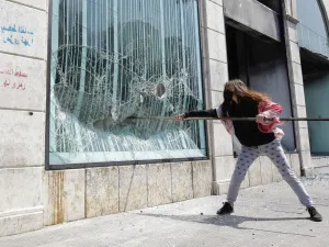 A Lebanese protester smashes the facade of a bank at Al-Nour square following the funeral of a fellow protester in Lebanon's northern port city of Tripoli, on April 28, 2020. Fawaz al-Samman's funeral was held in al-Nour Square, the main protest camp in the city of Tripoli, among dozens of mourners despite a nation-wide lockdown because of the coronavirus. Hundreds of demonstrators rocked Lebanon’s second city of Tripoli overnight, torching banks and vandalising ATM machines to denounce soaring inflation an