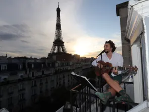 Singer Adrien Pelon aka "Adri1" performs from his balcony for his neighborhood on May 2, 2020, in Paris, as the country is under lockdown to stop the spread of the Covid-19 pandemic caused by the novel coronavirus. Ludovic MARIN / AFP