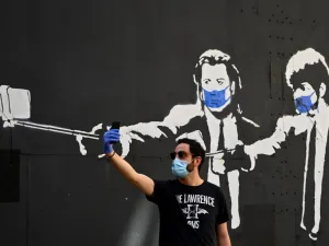 A man takes a selfie photo in front of a stencil graffiti depicting US actors John Travolta and Samuel L. Jackson in their roles of "Vincent Vega" and "Jules Winnfield" in Quentin Tarantino's "Pulp Fiction", wearing face masks, in Madrid on May 3, 2020 amid a national lockdown to prevent the spread of the COVID-19 disease. Spain today counted another 164 coronavirus deaths, the lowest daily number in nearly seven weeks as the country begins to gradually lift its strict lockdown. The figures from the health 