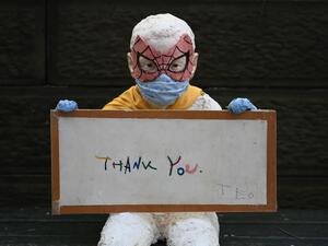 A statue of a child wearing a face mask and a spider man mask holds a "thank you" note for medical and essential workers outside The Mount Sinai Hospital during the the COVID-19 shutdown on May 4, 2020 in New York City. Angela Weiss / AFP