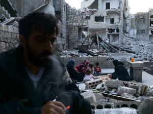 This picture taken on May 4, 2020 during the Muslim holy fasting month of Ramadan shows Tareq Abu Ziad (L), a displaced Syrian from the town of Ariha in the southern countryside of the Idlib province, smoking as members of his family break their fast together for the sunset "iftar" meal, in the midst of the rubble of their destroyed home upon their return to the town for one day after fleeing during the previous military assault by Syrian government forces and their allies. AAREF WATAD / AFP
