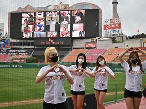 Cheerleaders pose in front of a big screen displaying baseball fans cheering from their homes during the opening game of South Korea's new baseball season between the SK Wyverns and Hanwha Eagles at Munhak Baseball Stadium in Incheon on May 5, 2020. South Korea's professional sport returned to action on May 5 after the coronavirus shutdown with the opening of a new baseball season, while football and golf will soon follow suit in a ray of hope for suspended competitions worldwide. Jung Yeon-je / AFP