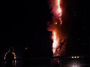People stand on a bridge and watch a fire that erupts in A 48-Storey Residential Tower in Sharjah on May 5, 2020. AFP