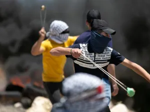 Tires burn as Palestinian youths use sling shots to hurl rocks at Israeli troops, during clashes with them in the West-Bank village of Kfar Qaddum, following a weekly demonstration against the expropriation of Palestinian land by Israel, on May 8, 2020. JAAFAR ASHTIYEH / AFP