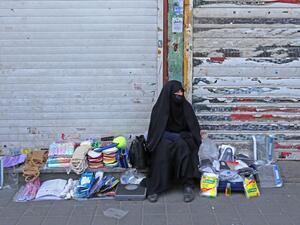 An Iranian street vendor wearing a protective mask amid the novel coronavirus pandemic, sits by her display of goods on a street of the capital Tehran, on May 09, 2020. ATTA KENARE / AFP