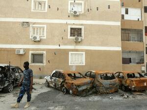 A fighter loyal to Libya's UN-recognised Government of National Accord (GNA) stands next to destroyed cars following bombardment earlier in the day in the residential Bab Bin Ghashir neighbourhood of Libya's capital Tripoli, on May 9, 2020. (AFP/File)