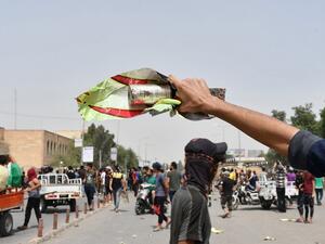 An Iraqi protester holds a smoke grenade fired by security forces amid clashes following an anti-government demonstration in Iraq's southern city of Nasiriyah in Dhi Qar province, on May 10, 2020. Iraq's new government promised to release demonstrators arrested during mass protests that erupted in October and pledged justice and compensation to relatives of over 550 people killed during that unrest. Asaad NIAZI / AFP