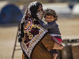 A displaced Syrian woman walks with her child at the Washukanni camp for the internally displaced in Syria's northeastern Hasakeh province on May 10, 2020, during the Muslim holy month of Ramadan. DELIL SOULEIMAN / AFP