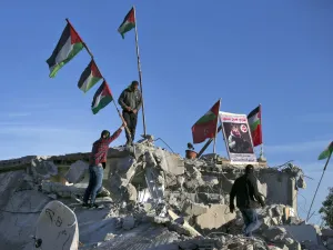 Palestinian men place a picture of Palestinian assailant Qassam Barghouti on the rublle of his family house after it was partially demolished by Israeli forces in the village of Kobar, near Ramallah, in the Israeli-occupied West Bank on May 11, 2020. Israeli forces demolished the home of a Palestinian accused of involvement in a bomb attack last year that killed an Israeli teenager in the occupied West Bank. The explosion on August 23, 2019, near a spring close to the Jewish settlement of Dolev, killed 17-y