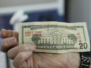 A customer pays with a $20 bill that has been stamped "Donald Trump Lives Here" after having his hair cut by barber Karl Manke, who faces two misdemeanor charges for reopening his business despite state shutdown orders, on May 12, 2020 in Owosso, Michigan. (AFP)