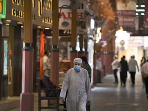 en wearing face masks, due to the COVID-19 coronavirus pandemic, walk past jewellers' shops at the Dubai Gold Souk in the Gulf emirate on May 13, 2020, as markets re-open amidst an easing of pandemic restrictions. (AFP)