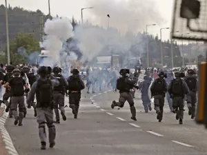 Tear gas fumes are seen as Israeli security forces run during clashes with protesters in a demonstration near the northern Arab Israeli city of Arara on May 14, 2020, after a man was shot to death after stabbing a security guard outside Tel Hashomer Hospital. Ahmad GHARABLI / AFP