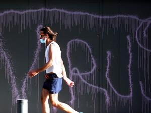 A man clad in mask due to the COVID-19 coronavirus pandemic walks past a graffiti reading "VIRUS" on the facade of a fortified local branch of the Bank of Beirut in the Lebanese capital on May 18, 2020. Lebanon is ready to terminate a 23-year-old dollar peg and float the pound, but only after it secures billions in aid, Finance Minister Ghazi Wazni had said on May 15. After talks started with the International Monetary Fund (IMF) on a plan to rescue Lebanon's crisis hit economy, he also said banking sector 