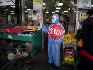 A worker wearing a full body suit holds a STOP sign in front of a Food market as he manages the flow of the customers on May 18, 2020 in the Jackson Heights neighbourhood of Queens in New York City. Johannes EISELE / AFP